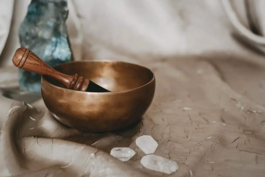 Bronze singing bowl with a wooden mallet resting inside